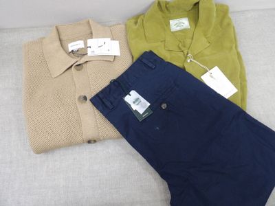 trois paires de vêtements pour homme posées les unes à côté des autres sur un canapé