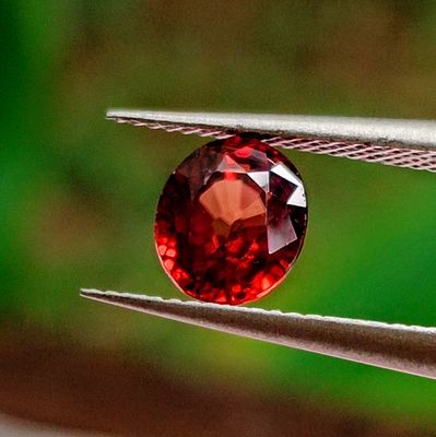 a close up of a red diamond being held by a pair of pliers