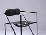 une chaise noire posée sur un sol blanc, près d'un mur blanc