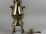 a silver coffee urn sitting on a stand next to a tea pot