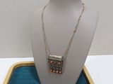 silver necklace with orange beads on display on a blue tray