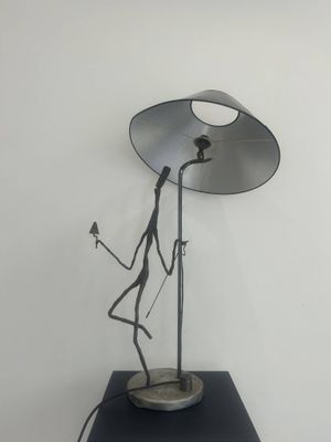 sculpture of a person holding a lamp on a table