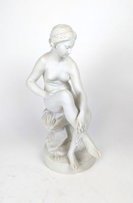 statue blanche représentant une femme assise sur un rocher, les mains posées sur les genoux