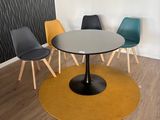 Des chaises aux couleurs vives sont disposées autour d'une table ronde dans une pièce