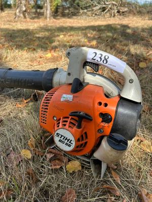 un souffleur de feuilles posé par terre dans l'herbe