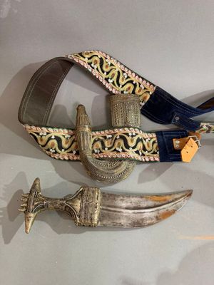 Deux couteaux et une ceinture sont exposés sur une table