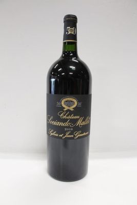 the bottle of wine is sitting on a white surface