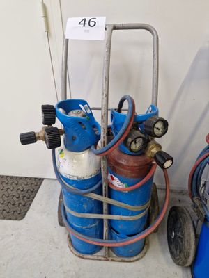 un chariot avec des bouteilles de gaz et des tuyaux posé par terre
