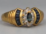 an image of a close up of a gold ring with blue and white stones