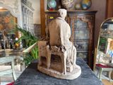 a statue of a man sitting on a chair in a living room