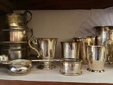 many silver cups and cups sitting on a shelf