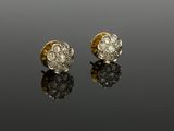 a pair of gold and diamond earrings on a reflective surface