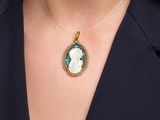 a close up of a woman wearing a necklace with a blue and white cameo