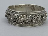 a close up of a silver bracelet on a gray surface