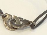 a silver bracelet with a bird on it on a white surface