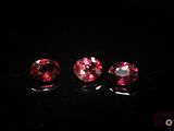 three pink tourmaline gems on a black surface