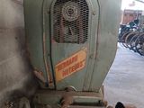 a old green tractor sitting in a garage next to a pile of motorcycles