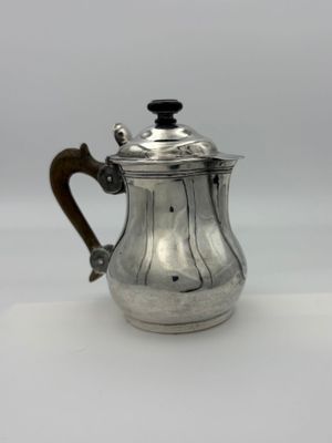 une cafetière ancienne en argent avec une poignée en bois sur un fond blanc