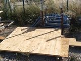 une plate-forme en bois posée à même le sol, près d'une clôture