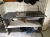 un évier de cuisine avec des casseroles et des poêles accrochées au mur