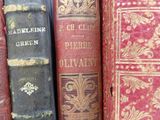 several old books are lined up in a row on a shelf