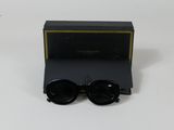 une paire de lunettes de soleil noires posée sur une table blanche