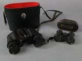 un sac noir muni d'une poignée rouge et d'une paire de jumelles