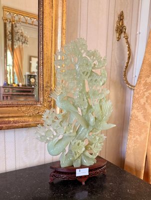 a vase with a plant on a table in front of a mirror