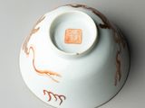 a white bowl with orange designs on it on a gray surface