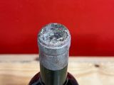 a bottle of wine sitting on a table with a red wall in the background