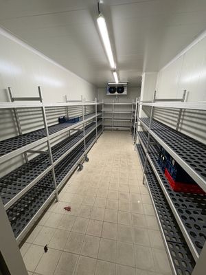 des rangées d'étagères métalliques dans une pièce blanche, avec un sac rouge posé par terre
