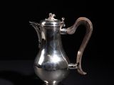 an antique silver coffee pot on a black background