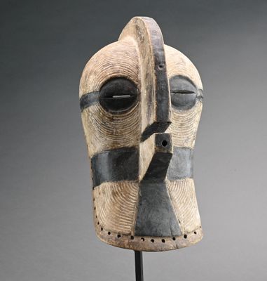 une image représentant un masque en bois posé sur un socle, sur fond gris