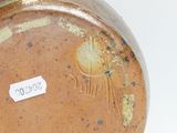 a brown vase with a label on it on a white surface