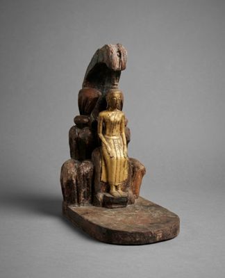 an old wooden statue of a woman sitting on a rock