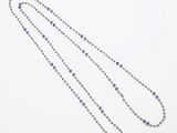 un gros plan d'un long collier de perles posé sur une surface blanche