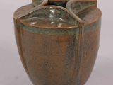 a brown vase that is sitting on a white surface