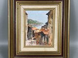 une peinture à l'huile représentant une scène de village, dans un cadre doré accroché au mur