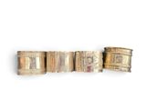 three gold bracelets with different designs on them on a white surface