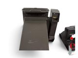a polaroid camera next to a roll of paper on a white surface