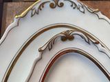 a white plate with gold trim on it on a wooden table