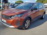 La voiture orange est garée sur le parking, à côté d'autres voitures.