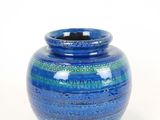 a blue vase that is sitting on a white surface