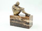 statue d'un homme assis sur un bloc de marbre, sur fond blanc