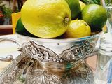 a silver bowl filled with lemons and limes on a table