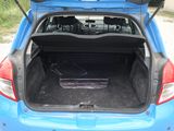 the back of a blue car with its trunk open on a gravel road