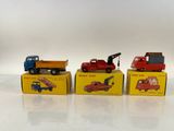 quatre camions miniatures sont alignés en rang sur une surface blanche