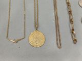 three gold necklaces and a coin on a table