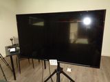 un grand téléviseur à écran plat posé sur un trépied dans un salon