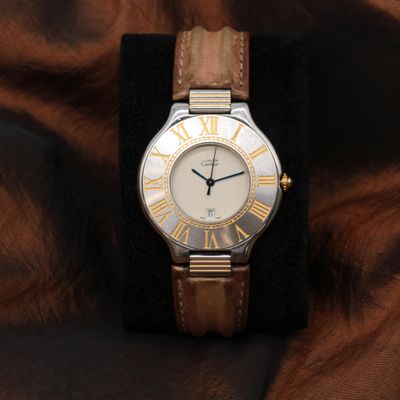 une photo d'une montre-bracelet avec des chiffres romains, montée sur un bracelet en cuir marron